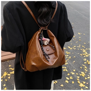 Brown faux leather convertible backpack with metal ring straps and plush charm detail