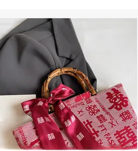 Detail of red bridal handbag with Double Happiness prints and natural bamboo handle