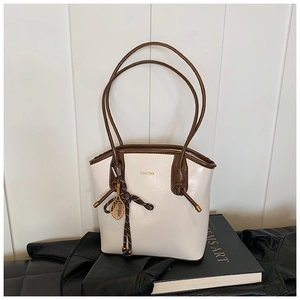 Détail du sac fourre-tout en cuir crème avec anses brunes et breloque raquette de tennis