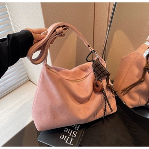 Pink suede hobo bag with adjustable wide strap and decorative charms for daily commuting