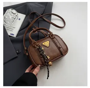 Close-up of brown leather Boston bag with golden triangle logo and stylish charms