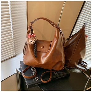 Detail of a brown leather hobo bag with ShellieMay plush charm on art books