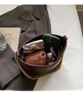Draufsicht auf das geräumige braune Stepptaschen-Innere mit goldener Kette und Zubehör