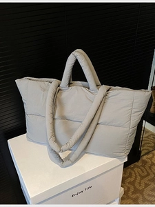 Gray quilted puffer tote bag with large squares and thick handles on white gift box
