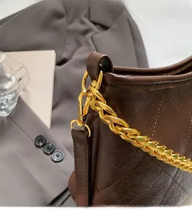 Nahaufnahme der braunen Stepp-Beuteltasche mit Goldkette und polierten Metallteilen
