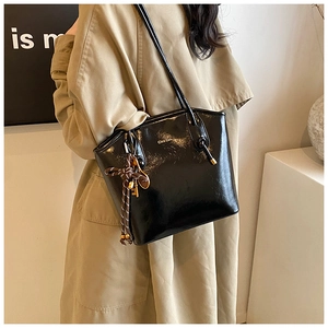 Détail du sac cabas noir brillant avec logo doré et bijou de sac raquette de tennis