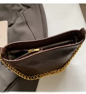 Detail des glatten Goldreißverschlusses und der Kette an der dunkelbraunen Stepptasche