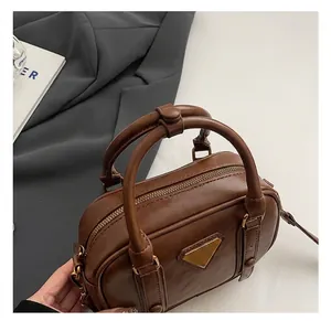 Detailed view of the brown leather handbag featuring round handles and golden triangle logo