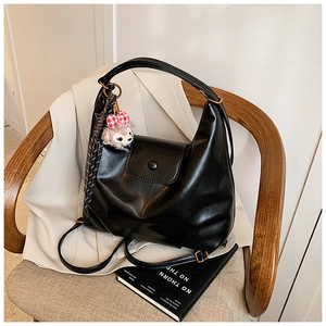 Detail of black crescent hobo bag in PU leather featuring a plush purple fox charm