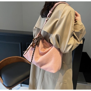 Detail of pink faux suede tote bag featuring braided side tassels and wooden pendant