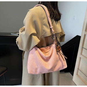 Detail of pink suede tote bag with heart buckle and decorative fringe tassel