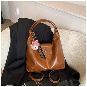 Brown PU leather hobo bag featuring a plush bear charm and striped ribbon detail