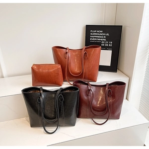 Detail of vintage oil wax leather tote bags with leaf-shaped stitching and small pouch