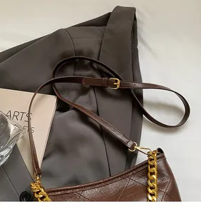 Detailansicht der dunkelbraunen gesteppten Beuteltasche mit Goldkette und Lederriemen