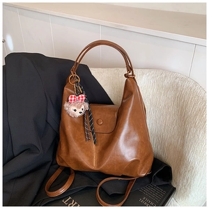 Detail view of large dark brown retro PU leather tote bag with a cute bear charm accessory