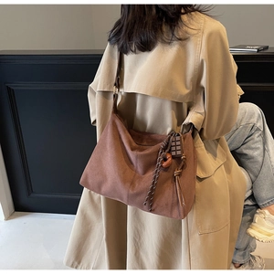 Detail view of large brown suede tote bag with chocolate charm and woven rope accent