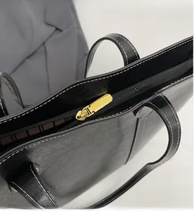Detail of smooth gold zipper and white contrast stitching on black textured tote bag