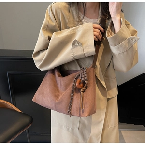 Detail of retro brown suede tote bag with chocolate charm and woven rope on model