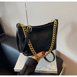 Detailansicht der schwarzen gesteppten Beuteltasche mit goldener Kette und Lederriemen