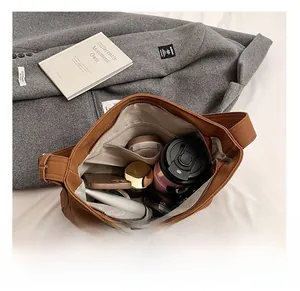 Top view of brown PU shoulder bag showing large interior capacity with personal items