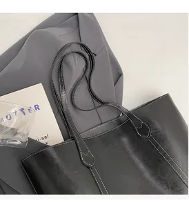 Detailed close-up of a black tote bag featuring distinctive white contrast stitching