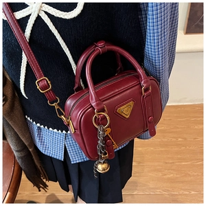Close-up of wine red vintage handbag with gold hardware and tassel charm detail