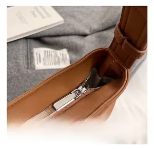 Close-up of premium silver metal zipper and herringbone fabric lining on a brown bag
