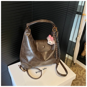 Detail of vintage dark brown PU leather shoulder bag with cute plush pendant and bow