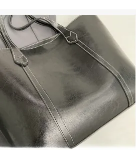 Detail of black tote bag showing vintage oil wax texture and contrast white stitching