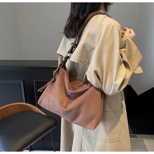 Detail of caramel brown suede hobo bag featuring adjustable leather strap and side knot detail