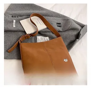 Detail of a brown tote bag with a silver cat-shaped metal logo on a grey woolen coat