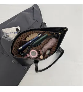 Top-down view of a spacious black tote bag showing its multi-compartment lining and storage