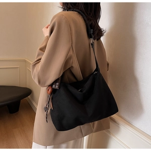 Close-up of black suede tote bag featuring unique chocolate and wooden ring charms