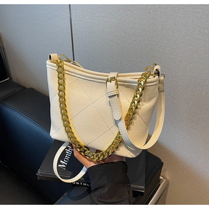 Detail der gesteppten Eimertasche mit Goldkette und cremefarbenem Schultergurt