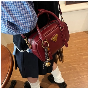 Detail of vintage burgundy Boston bag showing metal triangle plate and bell charm pendant