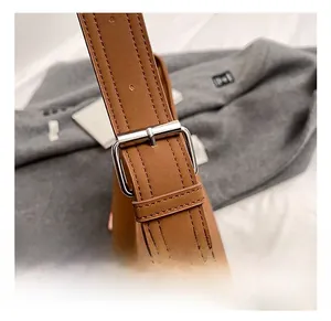 Detail of adjustable brown leather shoulder strap with silver metal buckle on a tote bag