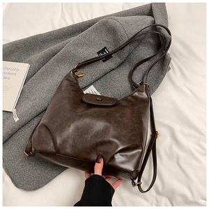 Detail of vintage dark brown faux leather hobo bag with pleated bottom and bronze hardware