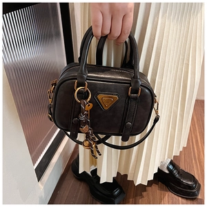 Detail of black vintage satchel with gold triangle hardware and woven rope ornament