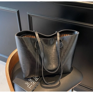 Detail of premium black leather tote bag with white stitching and striped fabric lining