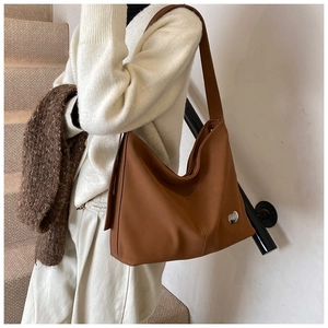 Detail of a brown Hobo bag with a silver cat-shaped metal emblem and soft leather texture