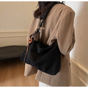 Detail of black canvas tote bag with unique chocolate charm and brown ring accessory