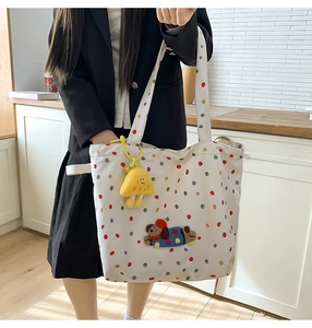Detail view of canvas tote bag with colorful dots, puppy embroidery and plush charm