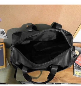 Top view of spacious black travel bag interior with reinforced handles and shoulder strap