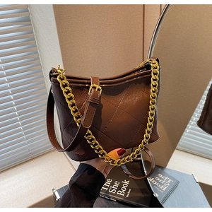 Detail der braunen gesteppten Beuteltasche mit Goldkette und verstellbarem Leder-Schultergurt