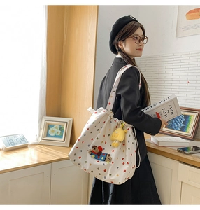 Detailed view of white polka dot canvas tote bag featuring cute bear embroidery and yellow charm