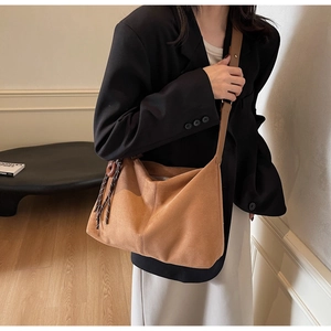 Detailed side view of brown suede tote bag with leather strap and wood ring charm