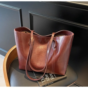 Detail of burgundy leather tote bag with contrast stitching on wooden chair setting