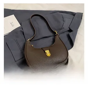 Detail of dark brown lychee leather hobo bag with polished golden metal buckle closure
