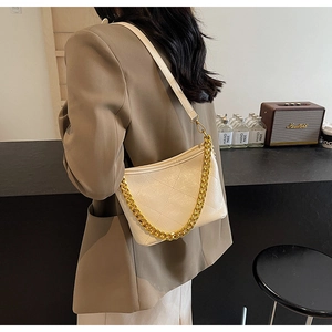 Detailansicht der gesteppten beigen Beuteltasche mit Goldkette und Riemen am Model