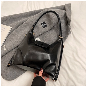 Detail of minimalist black hobo bag with gold ring hardware on stylish coat